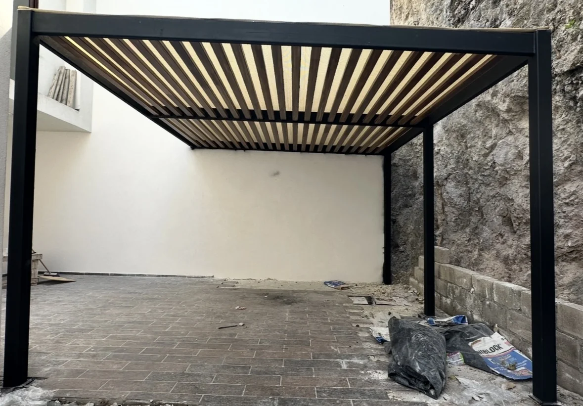 Pérgola de estructura metálica con lambrín de madera en obra residencial en Querétaro