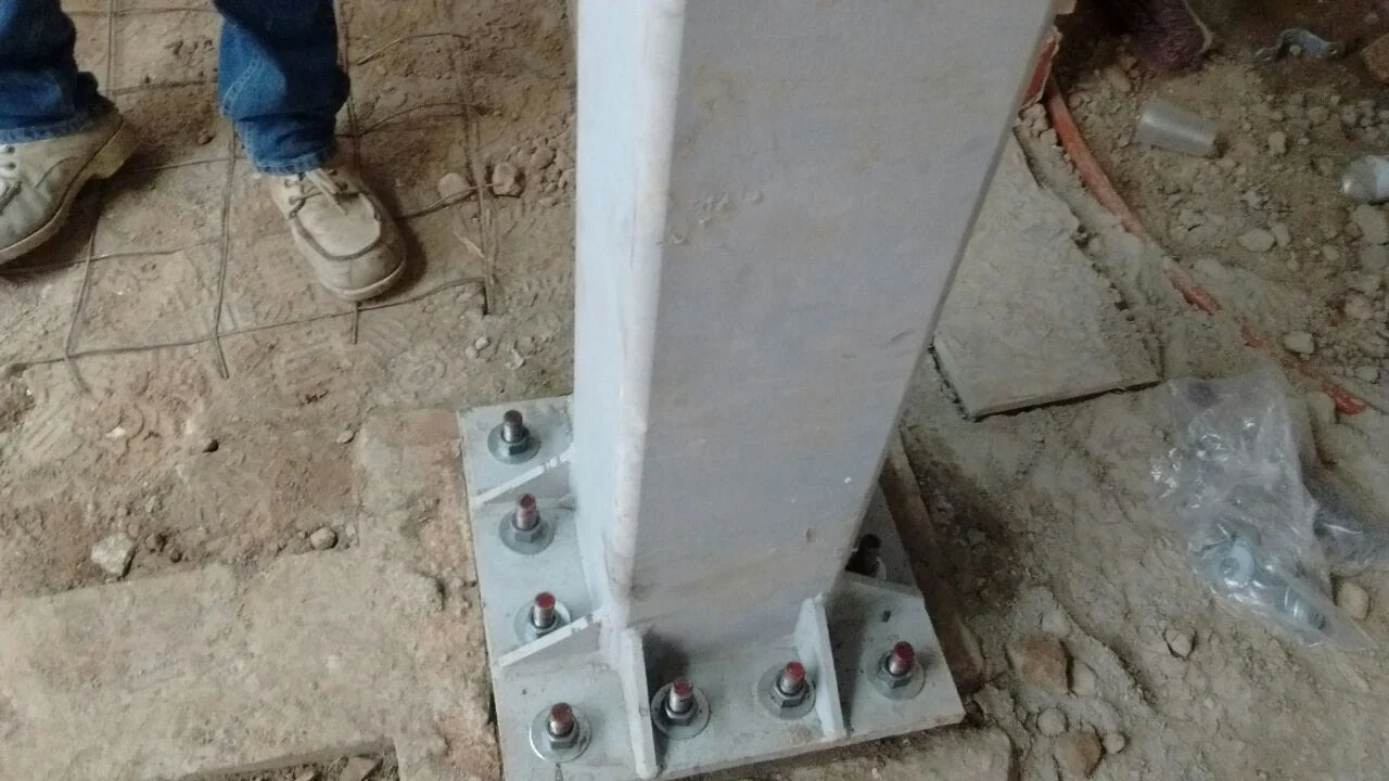 Placa base de columna metálica con anclas y tuercas de nivelación montada en obra