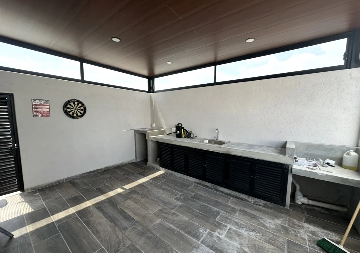 Terraza residencial terminada con plafón de madera, barra de concreto y ventanales en Querétaro
